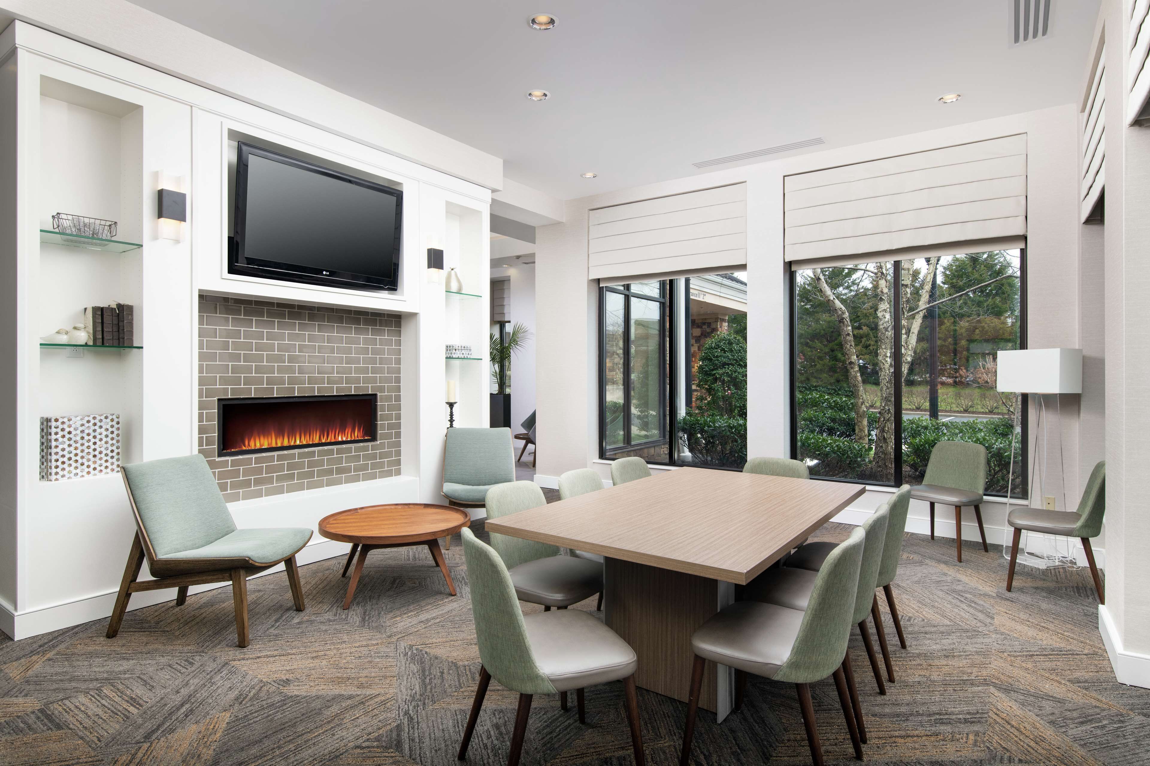 A modern living room with a fireplace, a large flat-screen TV, and a dining area with a wooden table and chairs.