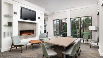 A modern living room with a fireplace, a large flat-screen TV, and a dining area with a wooden table and chairs.