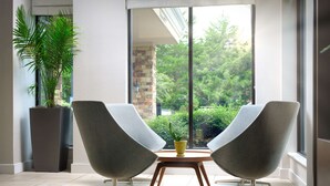 Una habitación moderna con dos sillas grises, una mesita y una planta en maceta.