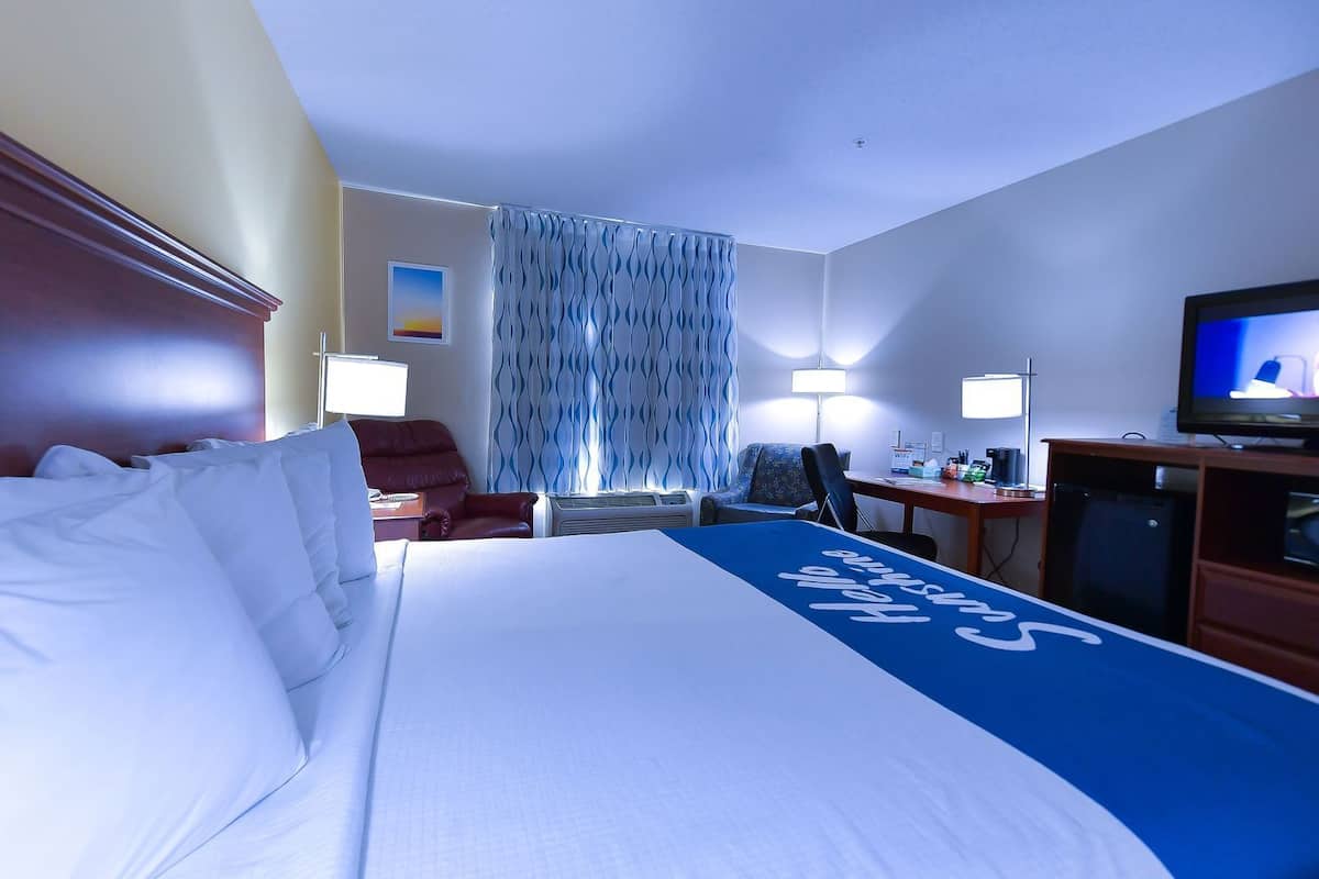 Een hotelkamer met een groot bed, een bureau met een computer, een televisie en een stoel.