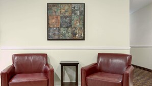 Two leather armchairs, a small wooden side table, and a framed abstract artwork on the wall. - Days Inn by Wyndham Greensboro NC (Greensboro)
