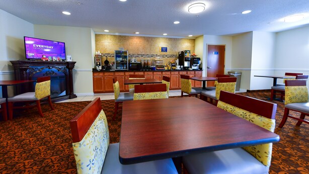 A hotel lobby with a bar area, seating arrangements, and a television displaying 'Everyday Heroes'. - Days Inn by Wyndham Greensboro NC (Greensboro)