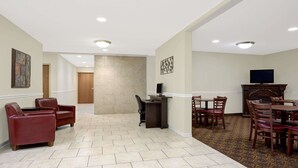 A hotel lobby with a reception desk, seating area, and a television. - Days Inn by Wyndham Greensboro NC (Greensboro)