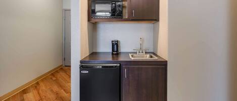 A compact kitchen with a built-in microwave, a coffee maker, and a sink.