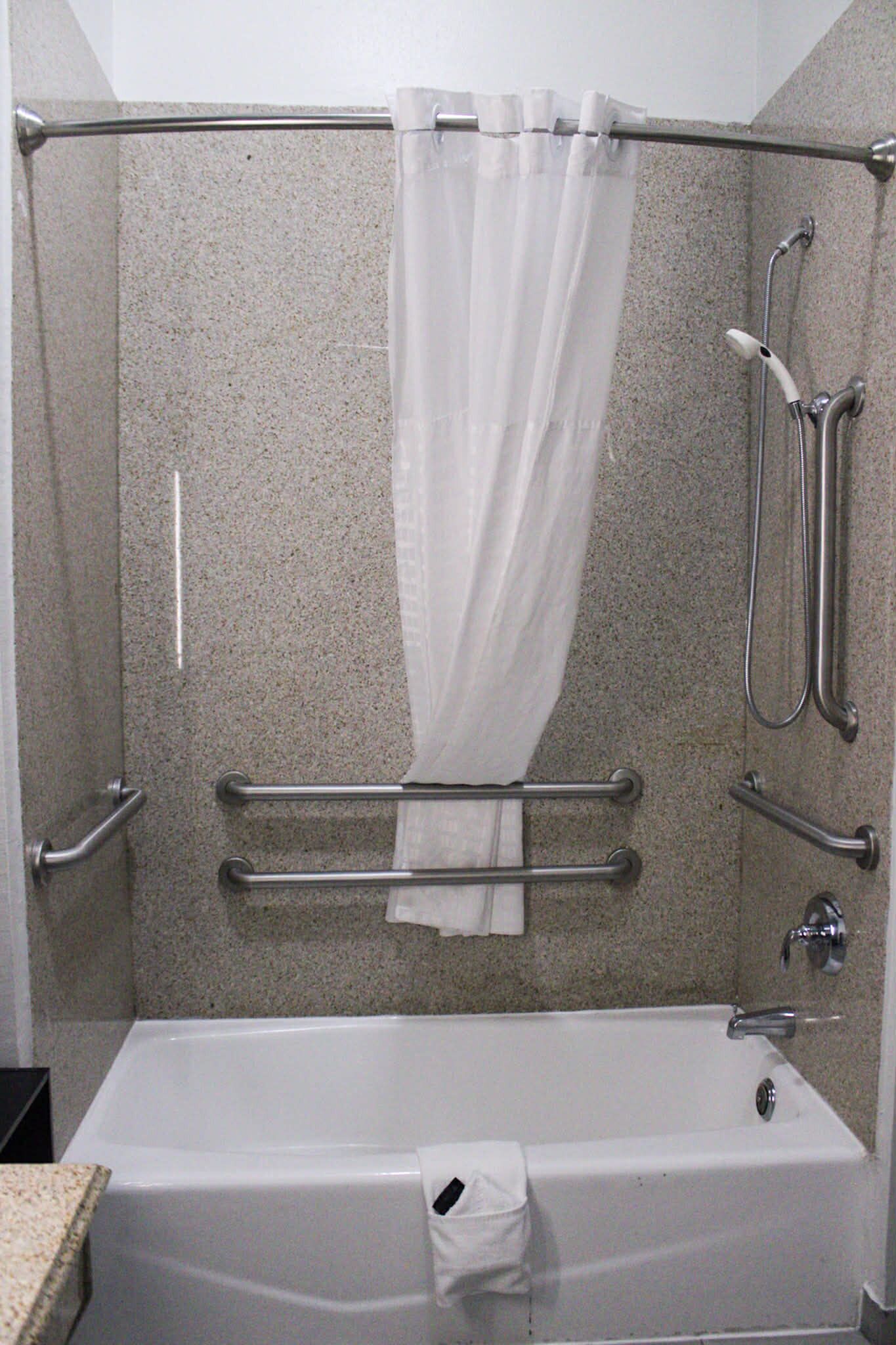 Une douche avec une porte en verre, un pommeau de douche à main et un porte-serviettes.