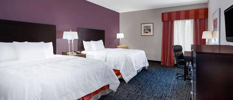 A hotel room with two beds, a desk, a chair, and a TV.