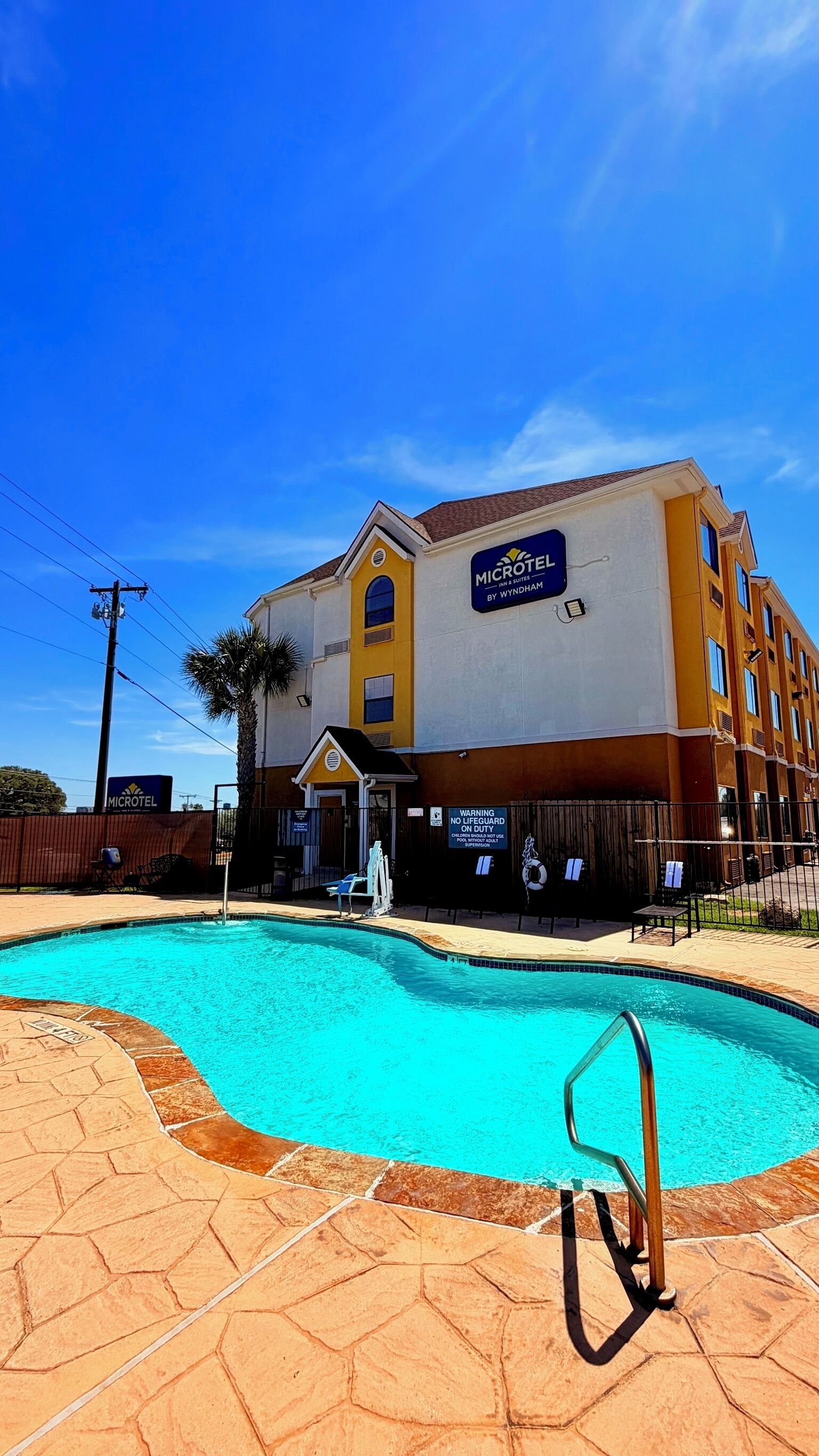 A Microtel Inn by Wyndham with a swimming pool, outdoor seating, and a fenced area.