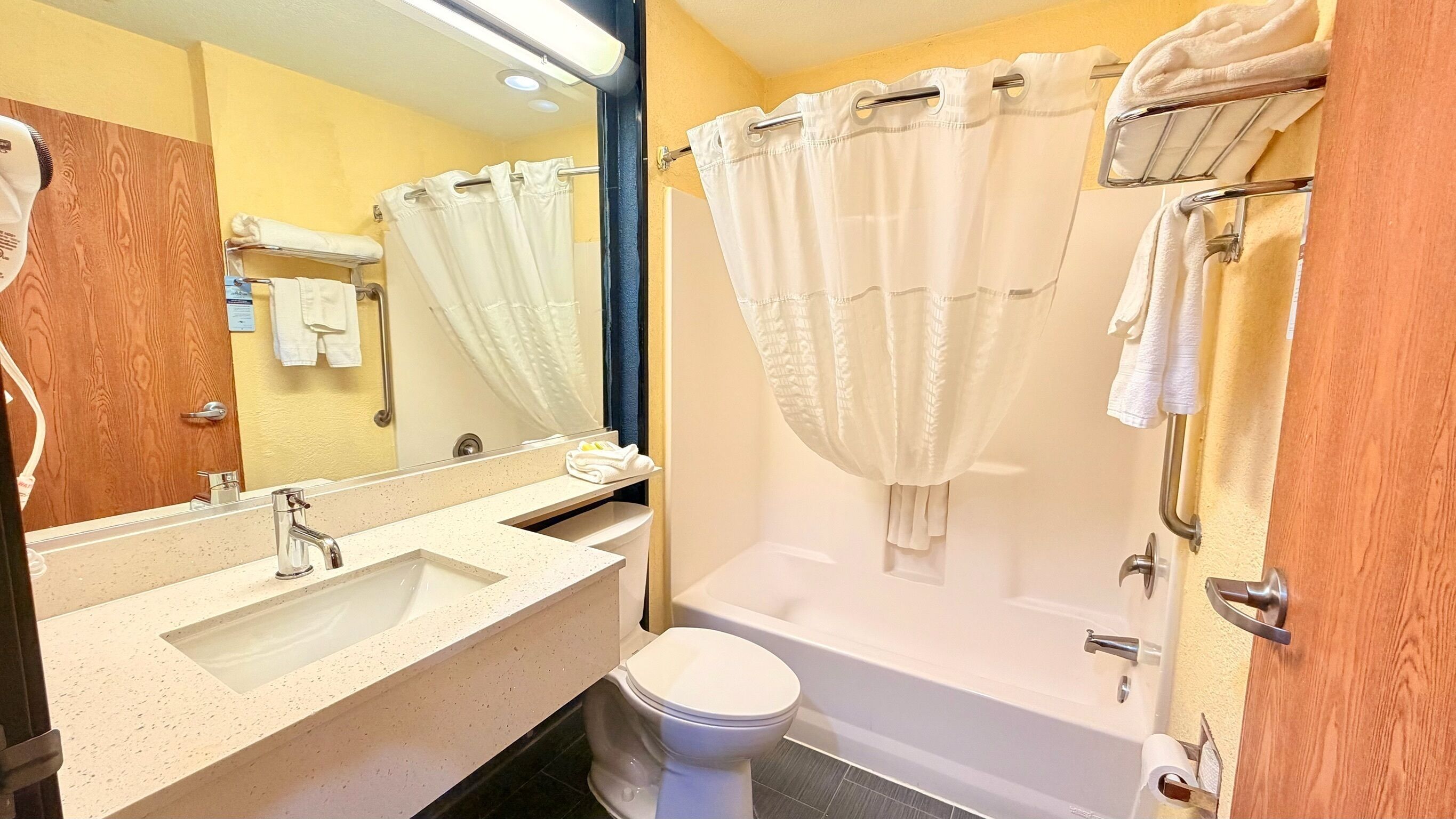 Ein Badezimmer mit Waschbecken, Spiegel, Toilette und Badewanne.