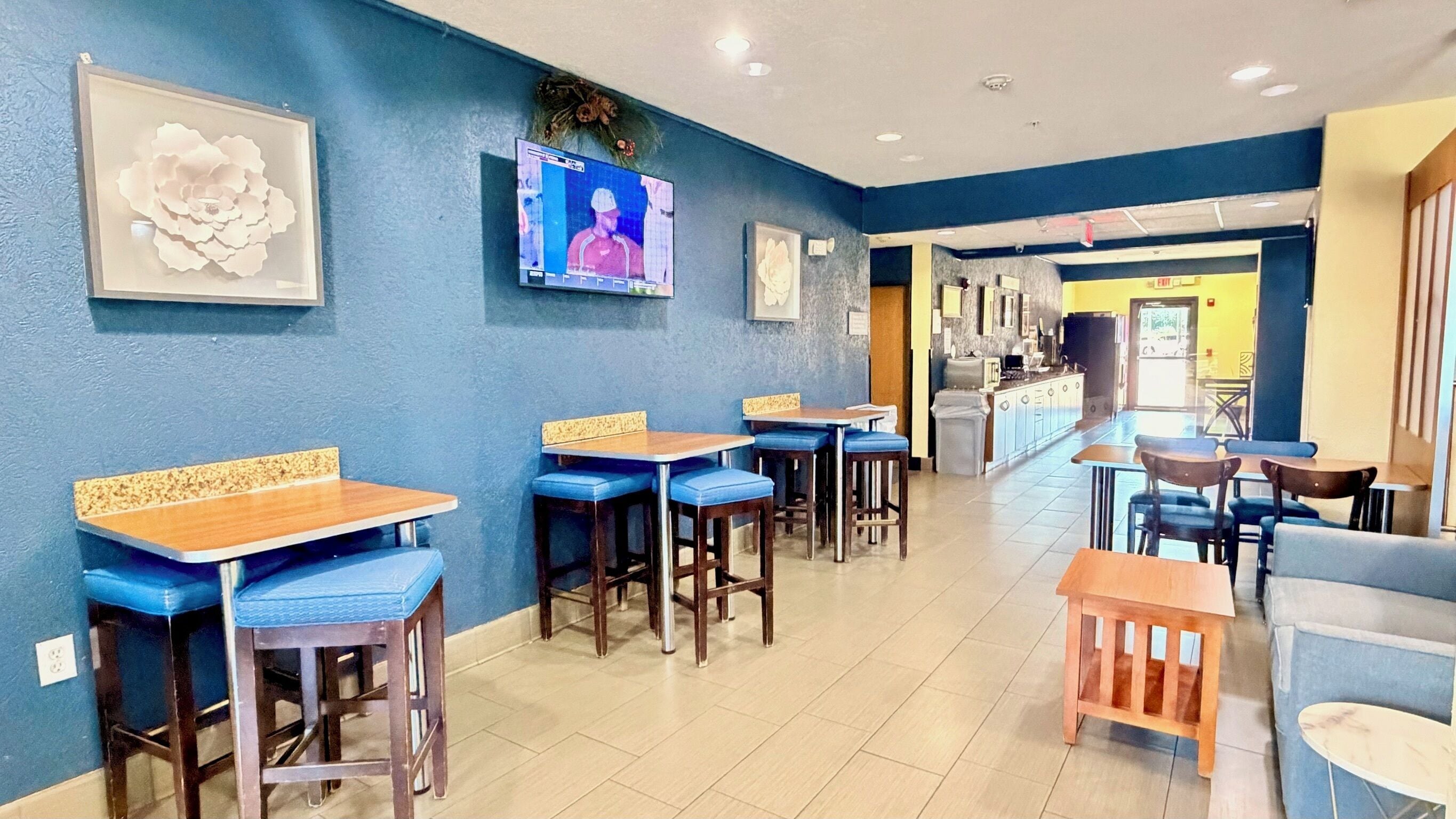 Un restaurant amb parets blaves, taules de fusta i cadires blaves amb coixinets.
