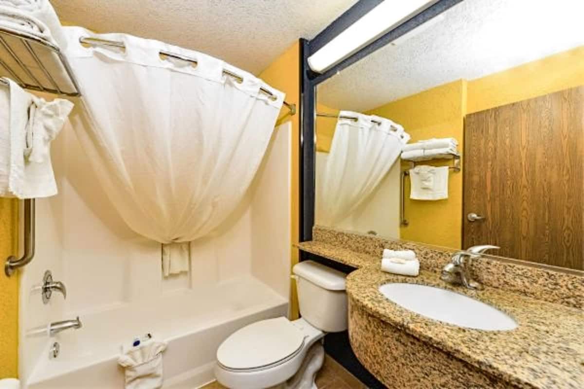 A bathroom with a bathtub, toilet, sink, and mirror.
