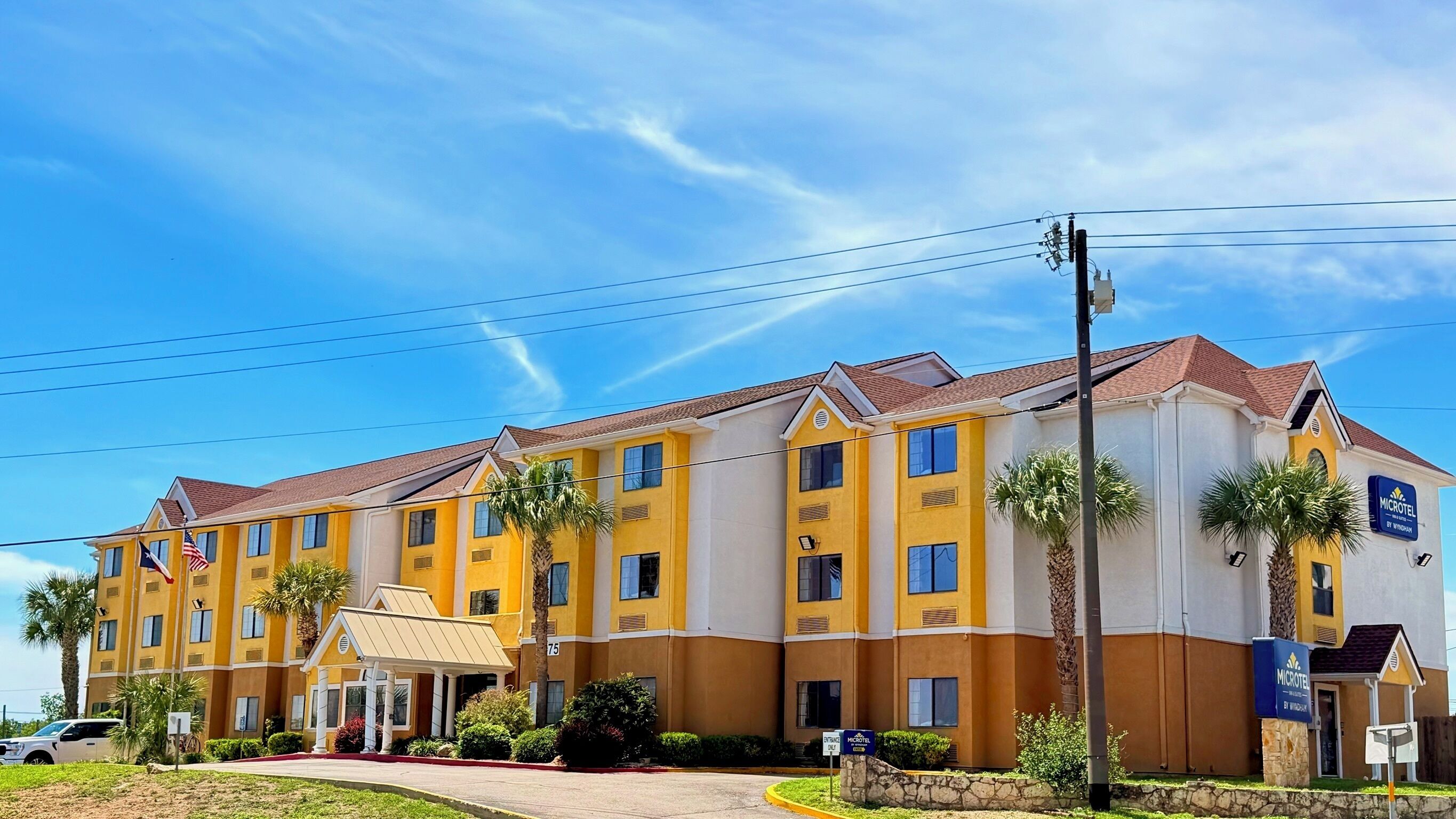 A multi-story hotel with a yellow facade, multiple windows, and a sign for the Microlodge by Wyndham.