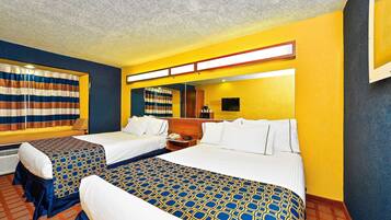A hotel room with two beds, a large window with striped curtains, a flat-screen TV, and a mirror on the wall.