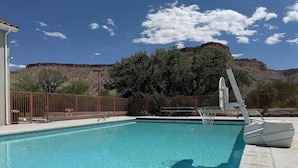 Piscina con una cerca metálica, un puesto de salvavidas y montañas al fondo.