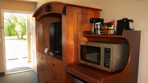Una cocina compacta con microondas, cafetera y un refrigerador pequeño.