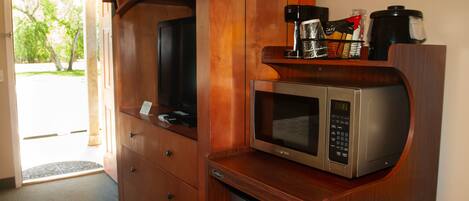 A compact kitchen with a microwave, coffee maker, and a small refrigerator.