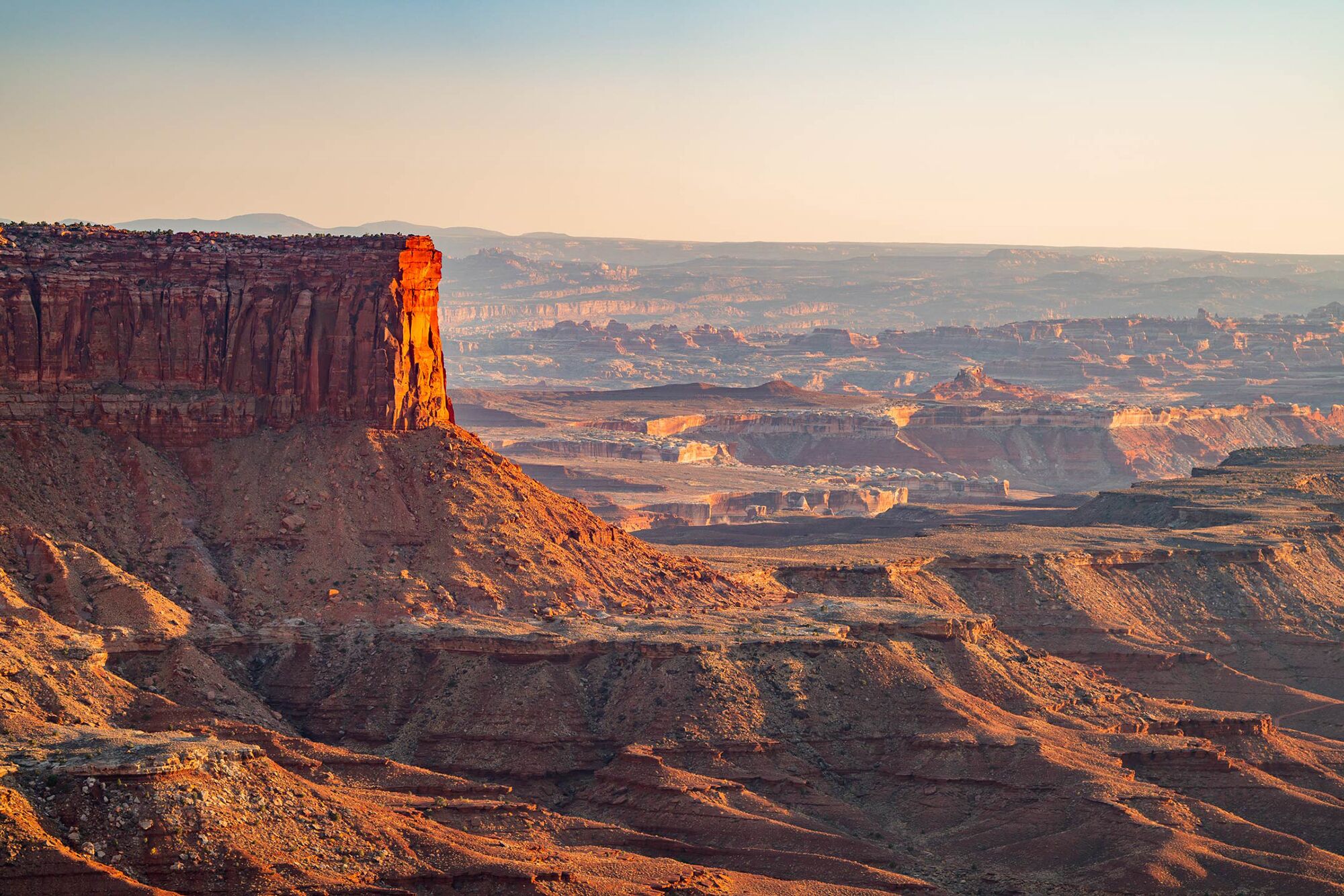 A vast canyon landscape with layered rock formations and a prominent cliff.