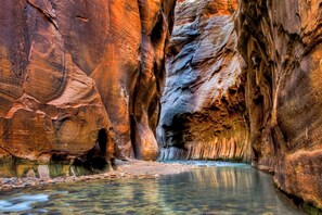 A narrow canyon with a clear stream at the bottom.