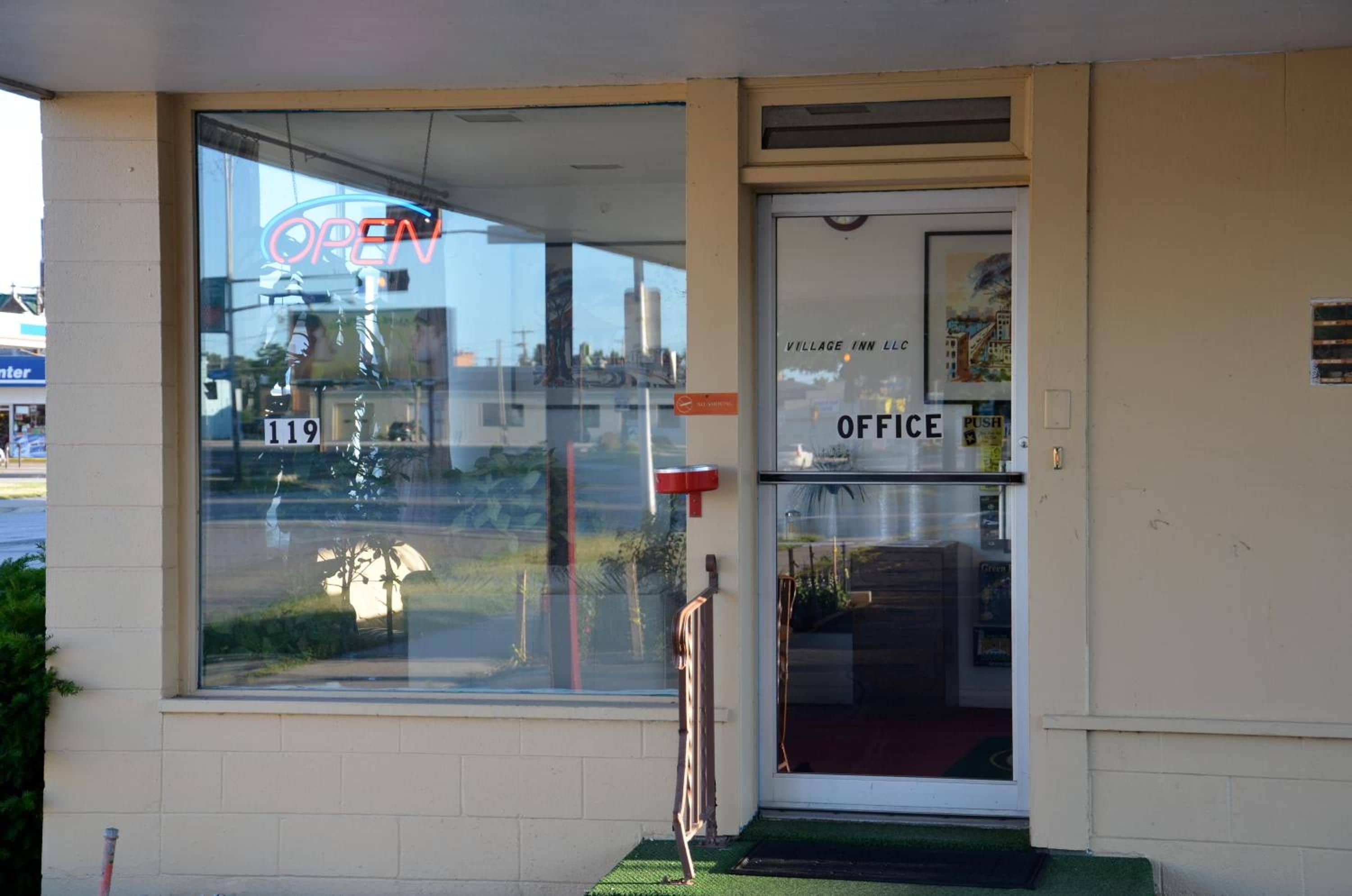 A hotel entrance with a large window displaying the number 119, an 'OPEN' sign, and an 'OFFICE' sign.