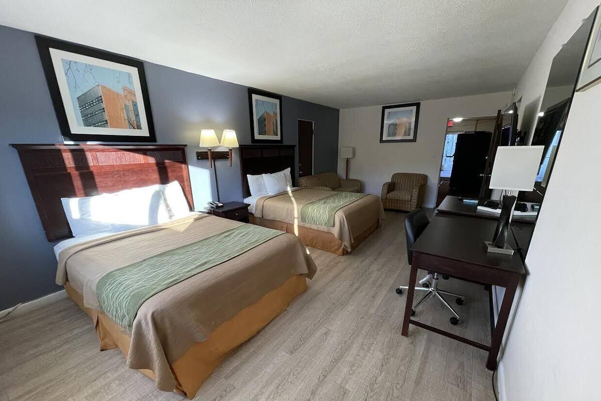 A hotel room with two beds, a desk, and a chair.
