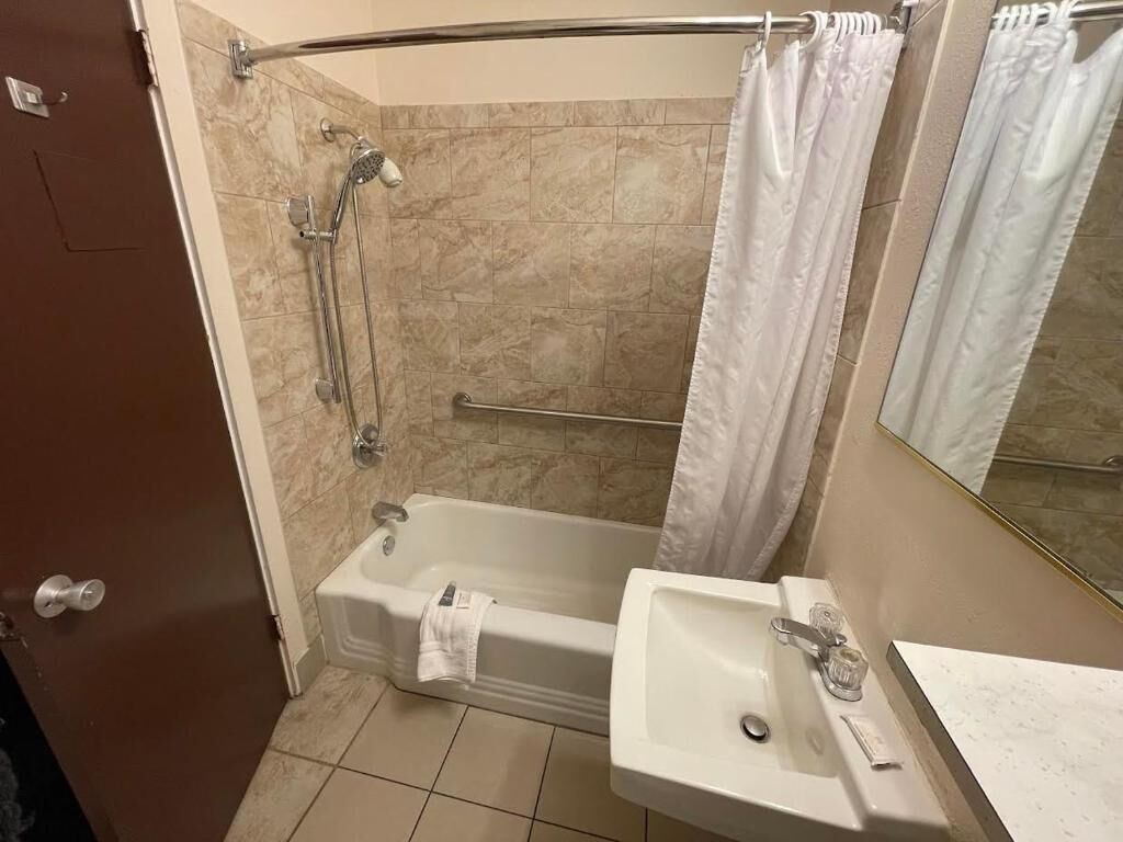 Een badkamer met een bad, douche en wastafel.