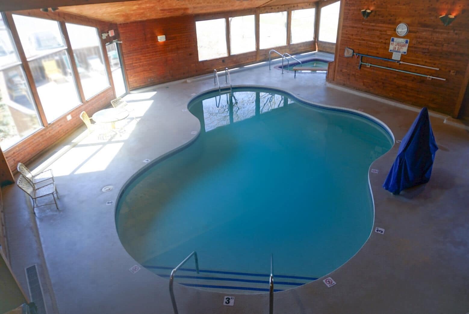 An indoor swimming pool with a wooden interior, clear glass walls, and a lifeguard station.