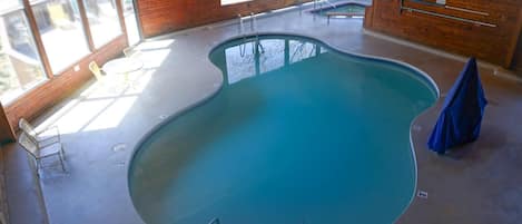An indoor swimming pool with a wooden interior, clear glass walls, and a lifeguard station.