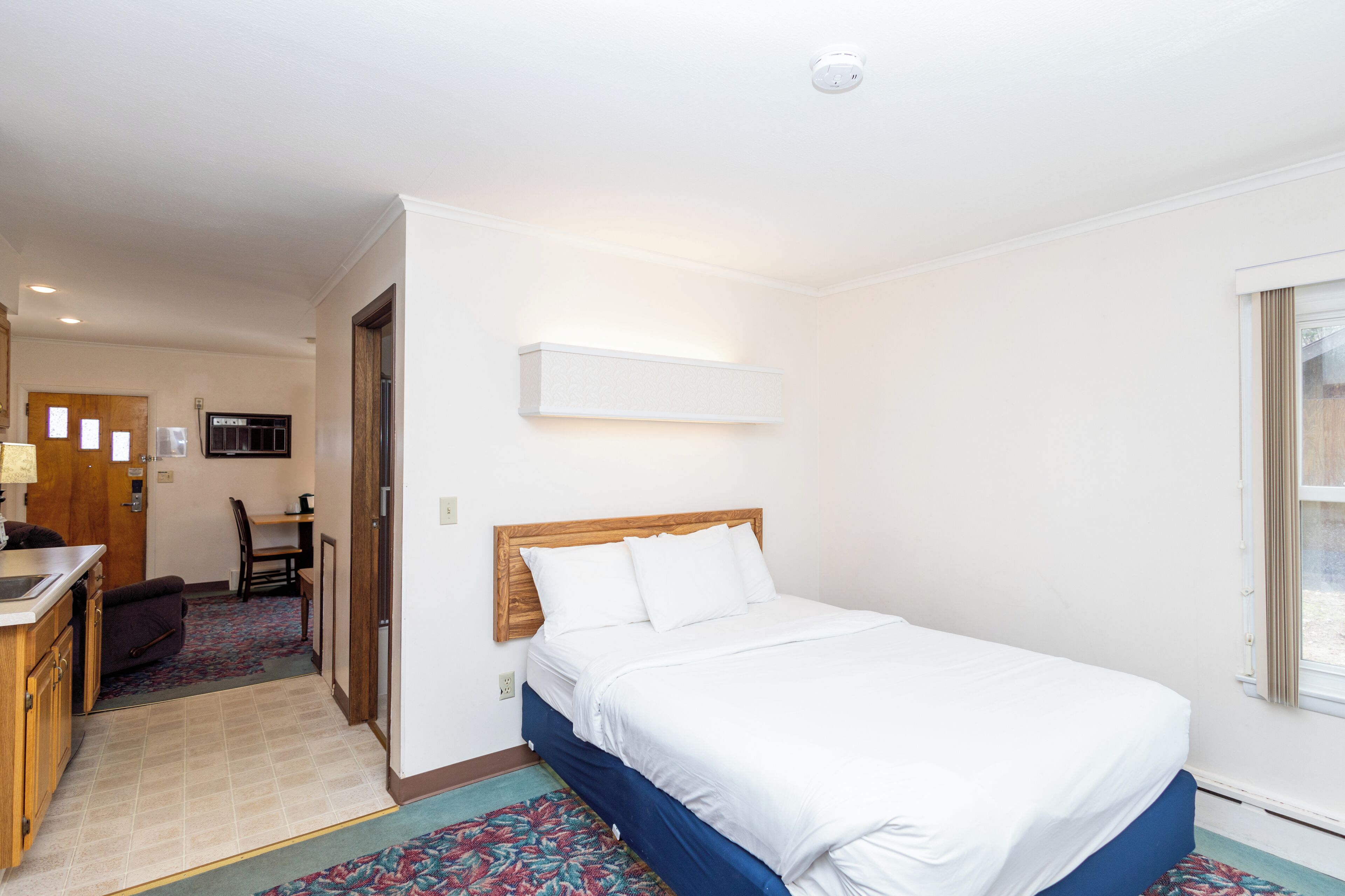 A hotel room with a bed, a desk, and a chair.