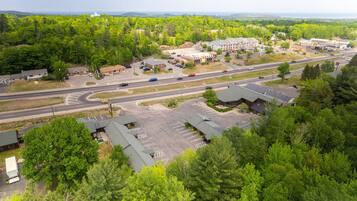 Vue aérienne d’une zone commerciale comprenant un parking, des bâtiments et une route.