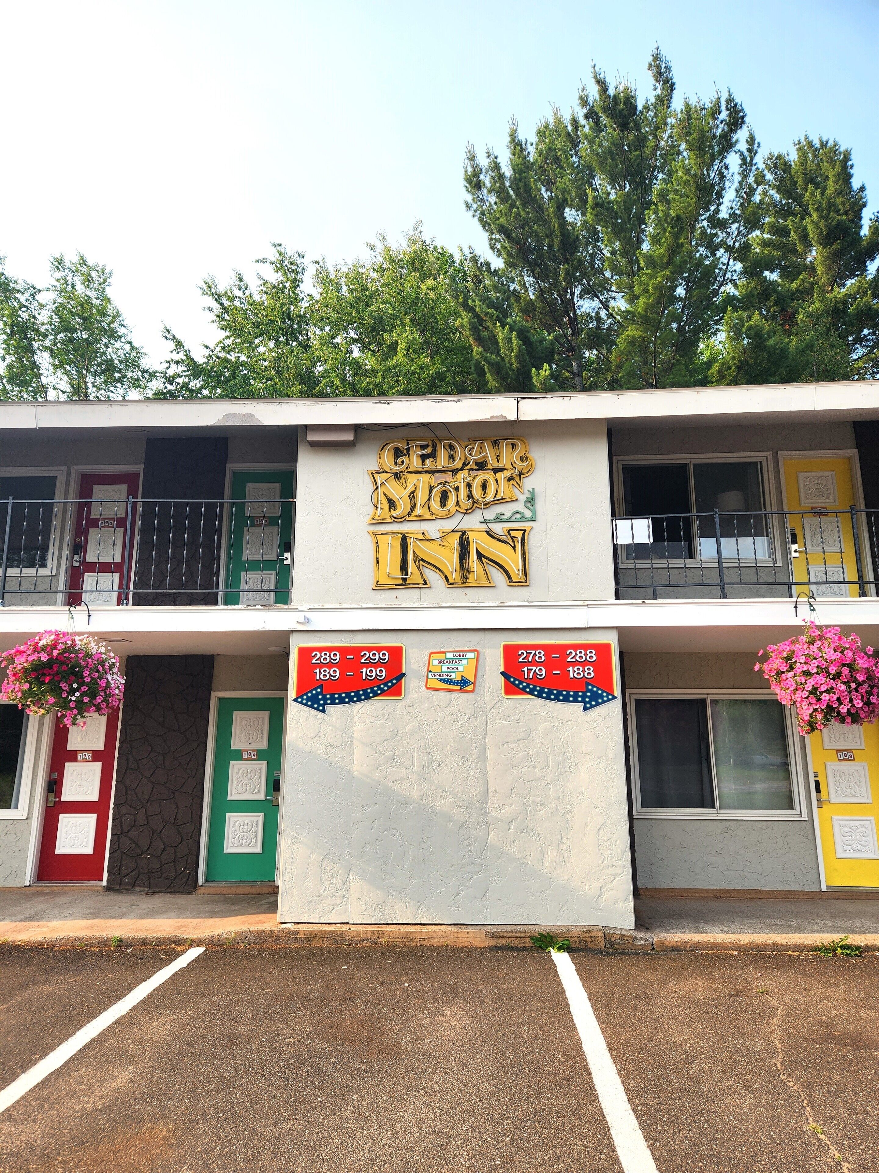 A Cedar Motor Inn with a signboard, three doors, and price tags for different room types.