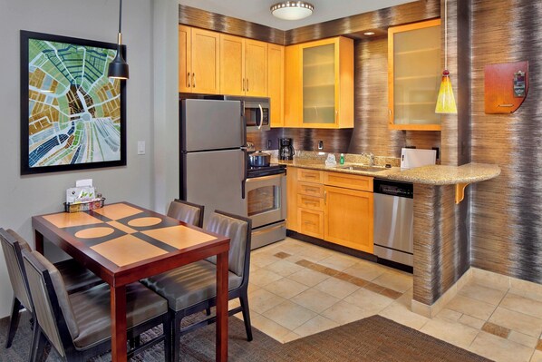 A modern kitchen with wooden cabinets, a stainless steel refrigerator, a microwave, and a coffee maker.
