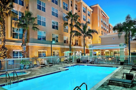 Una piscina al aire libre, sombrillas, sillones reclinables de piscina