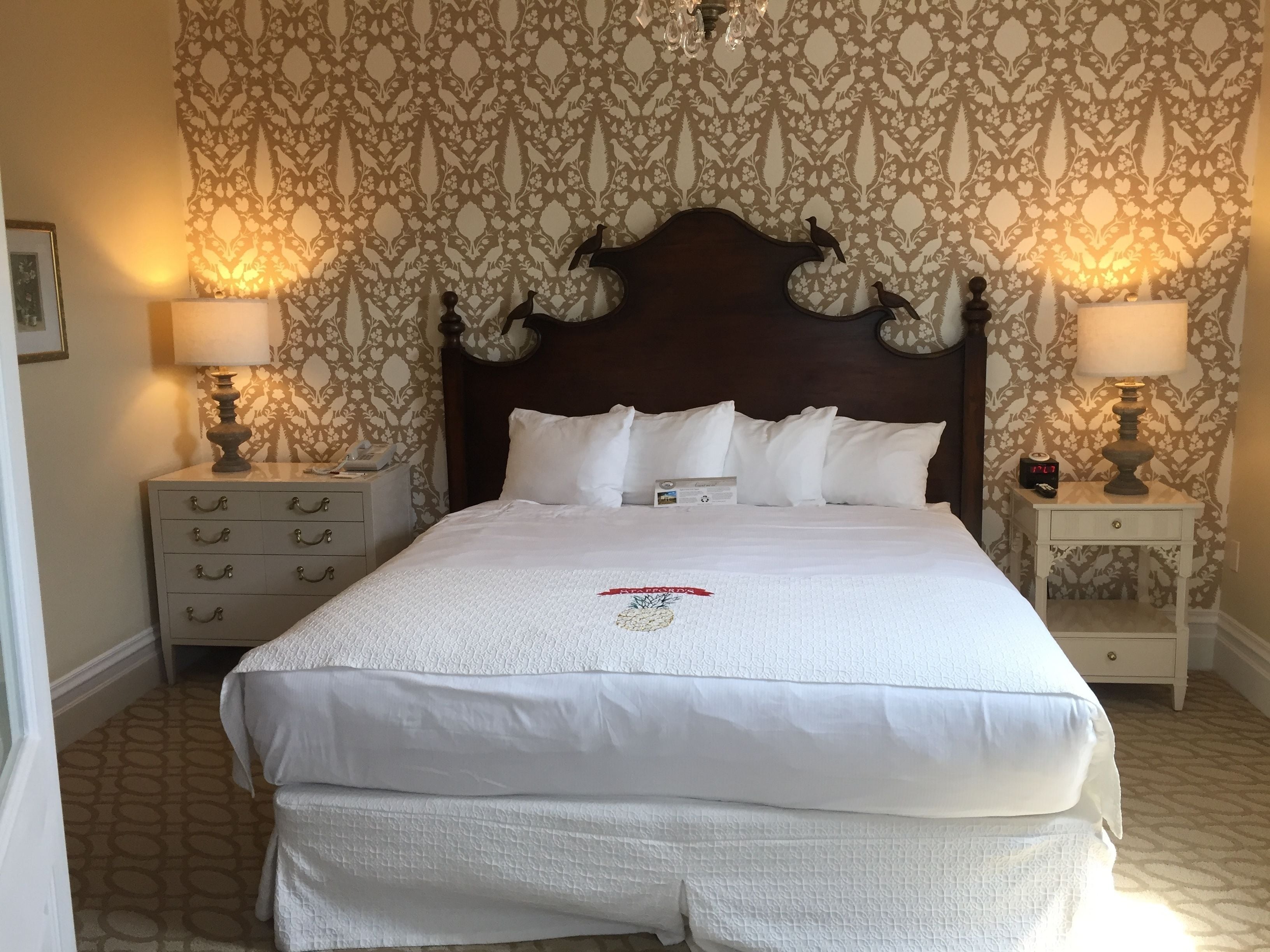 A neatly made bed with a decorative pillow and a quilted cover, flanked by two bedside tables with lamps and clocks.