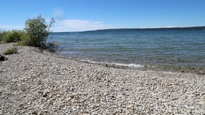 A pebbly beach with clear water and distant land. - Hotel Perry (Petoskey)