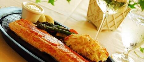 A plate with salmon, asparagus, and hollandaise sauce, accompanied by a glass of white wine and a glass of water.