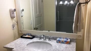 Un bagno con uno specchio grande, un lavandino, un asciugacapelli e un portasciugamani.