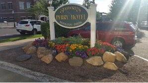 A sign for the Perry Hotel with a flower bed and rocks in front. - Hotel Perry (Petoskey)