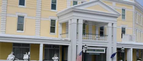A yellow building with a white facade, a central entrance with columns, and a sign reading "BERRY HOTEL".
