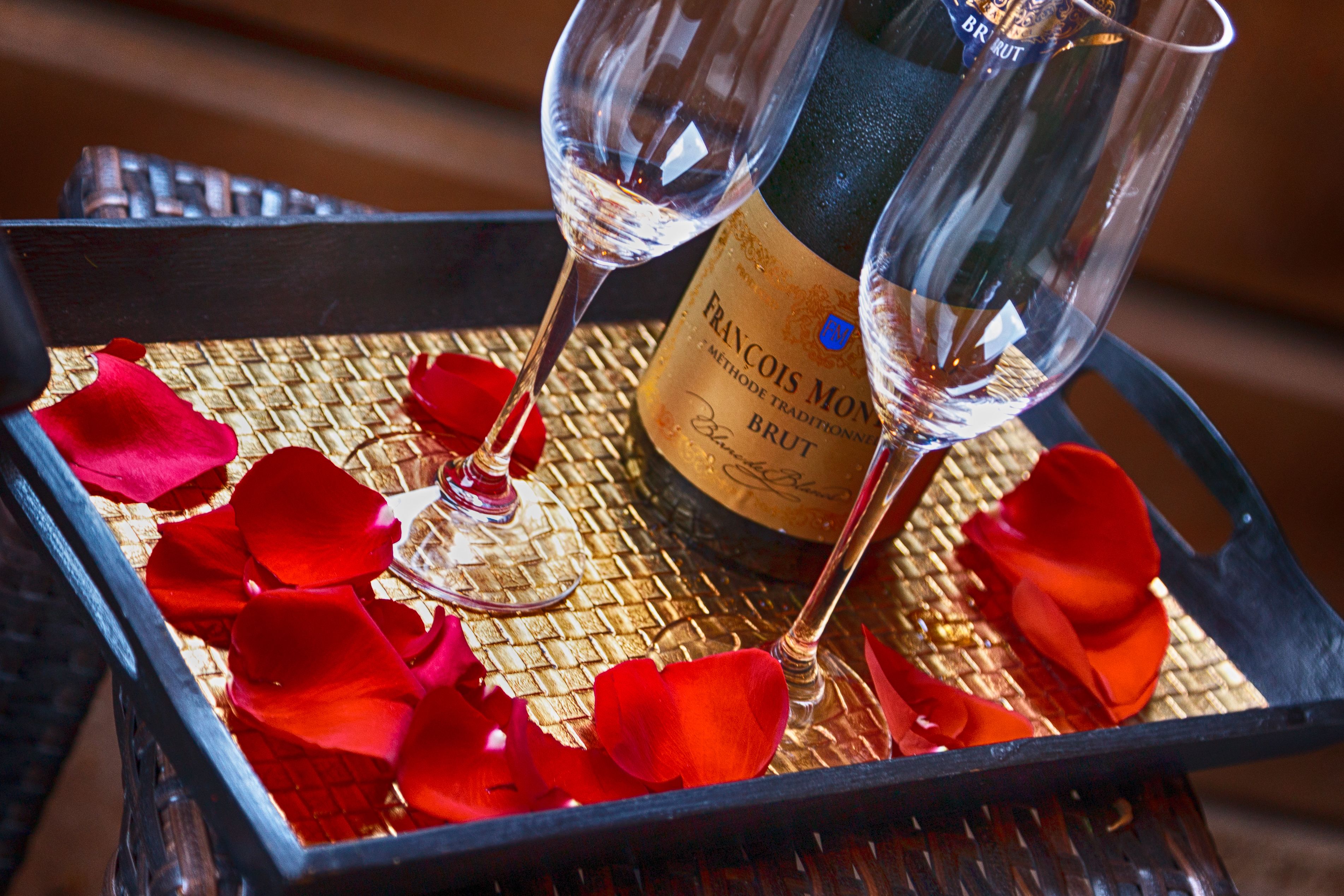 A bottle of Francois Moët Brut champagne and two glasses on a tray with rose petals.