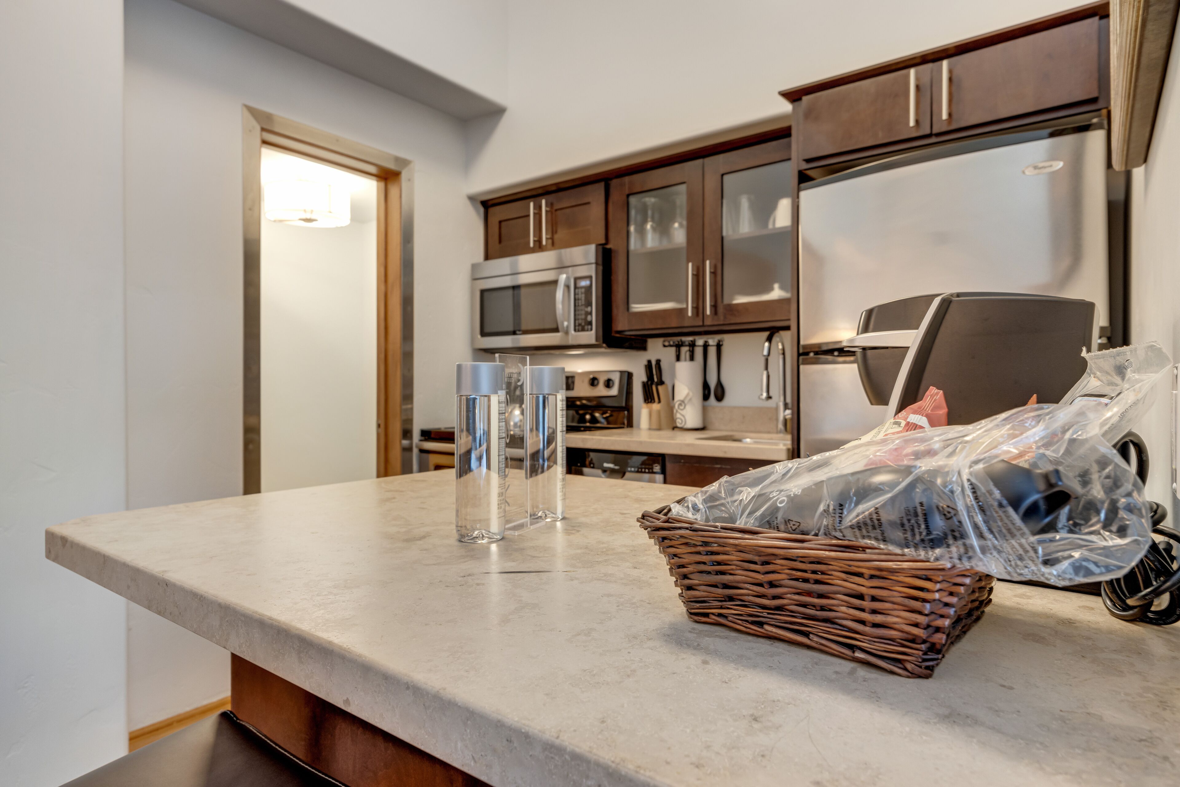 A kitchen with a marble countertop, stainless steel appliances, and a wicker basket on the counter.