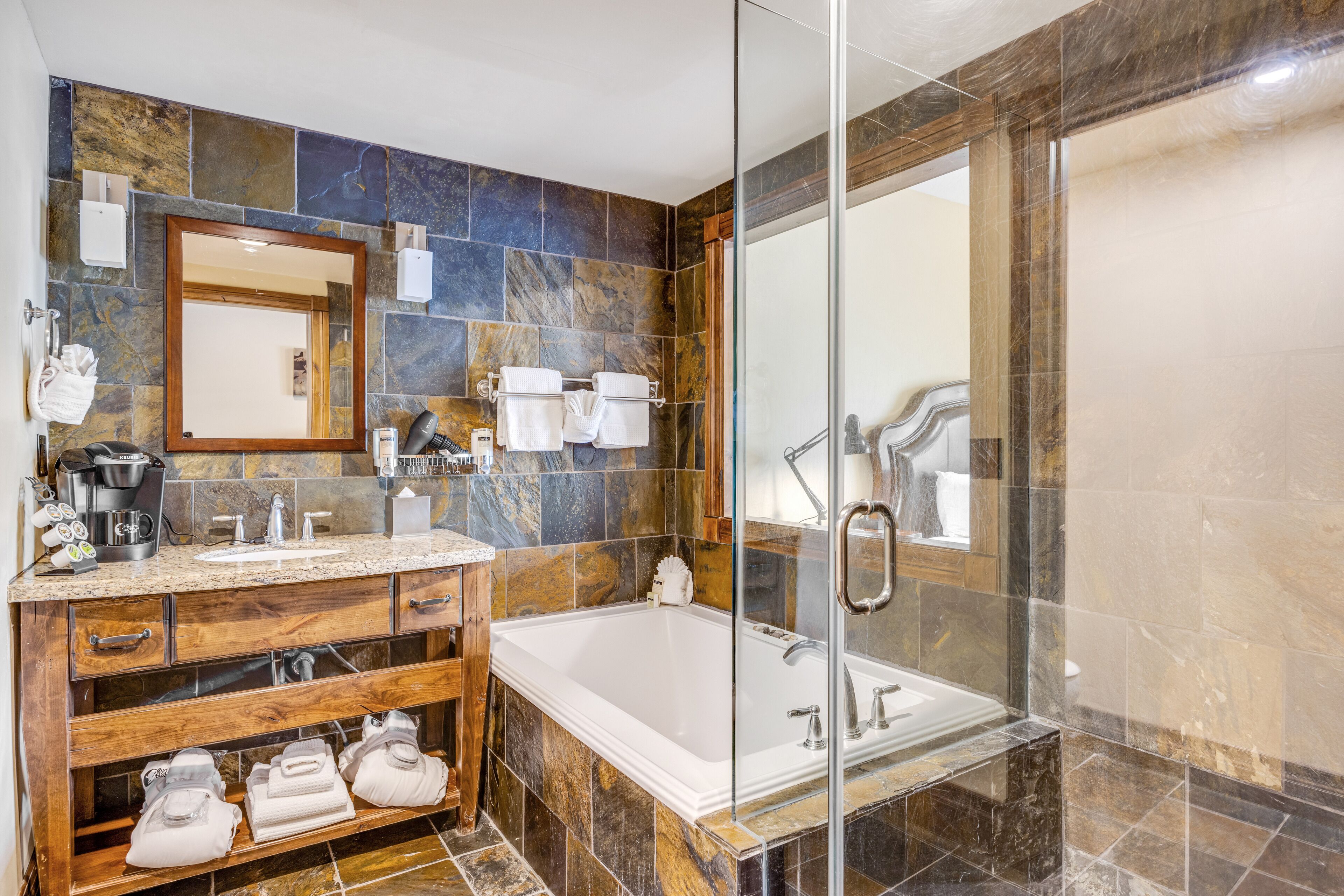 Et moderne badeværelse med et stort badekar, en brusekabine med glasvægge og et toiletbord med marmorplade.