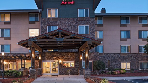 Un hotel TownePlace Suites Marriott con fachada de piedra, varias ventanas y un acceso cubierto.