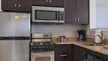 A modern kitchen with dark cabinets, stainless steel appliances, and a granite countertop.
