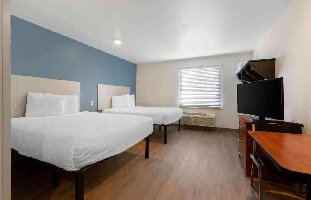 A hotel room with two beds, a TV, and a desk.