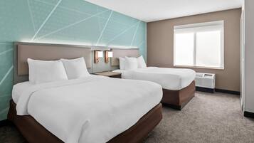A hotel room with two beds, a large window, and a wall with geometric patterns.