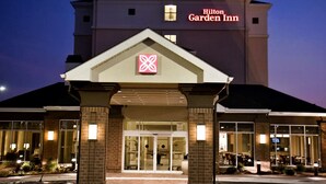 Exterior d'un Hilton Garden Inn amb un logotip ben visible, façana de maó i grans portes de vidre.