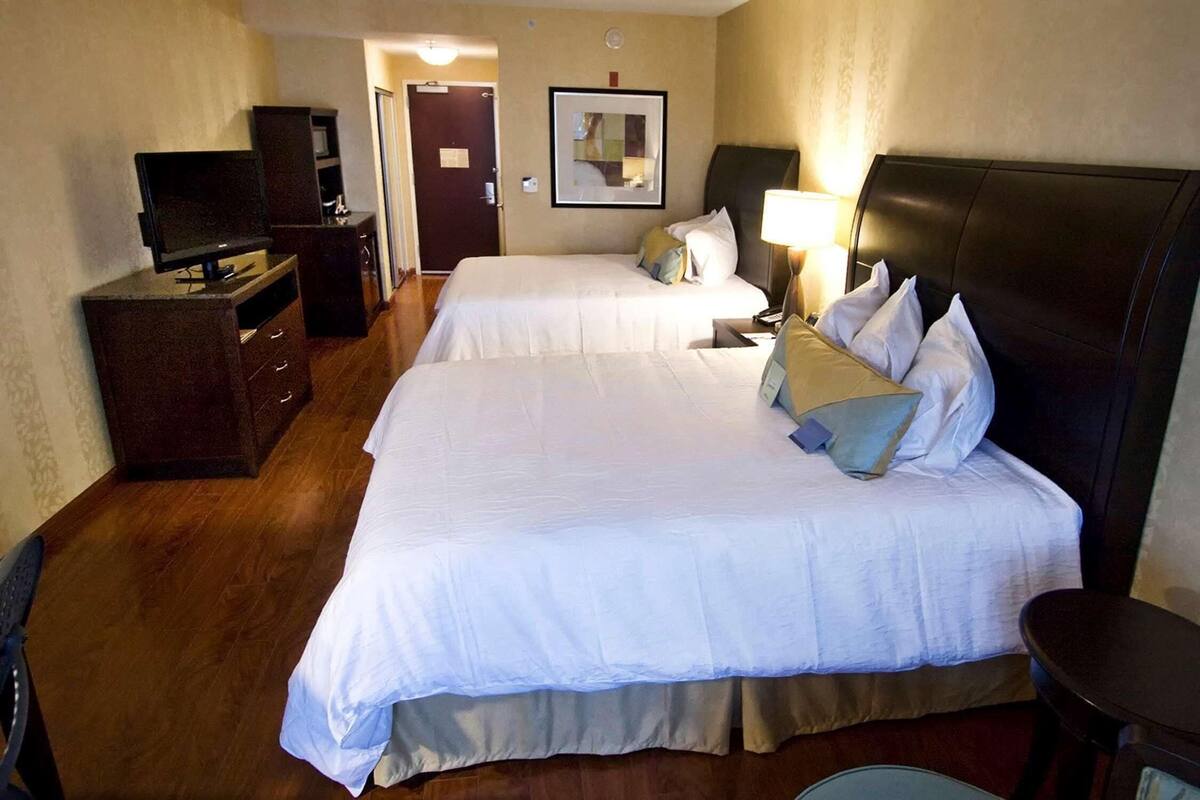 Ett hotellrum med två sängar, en TV, ett skrivbord och en spegel.