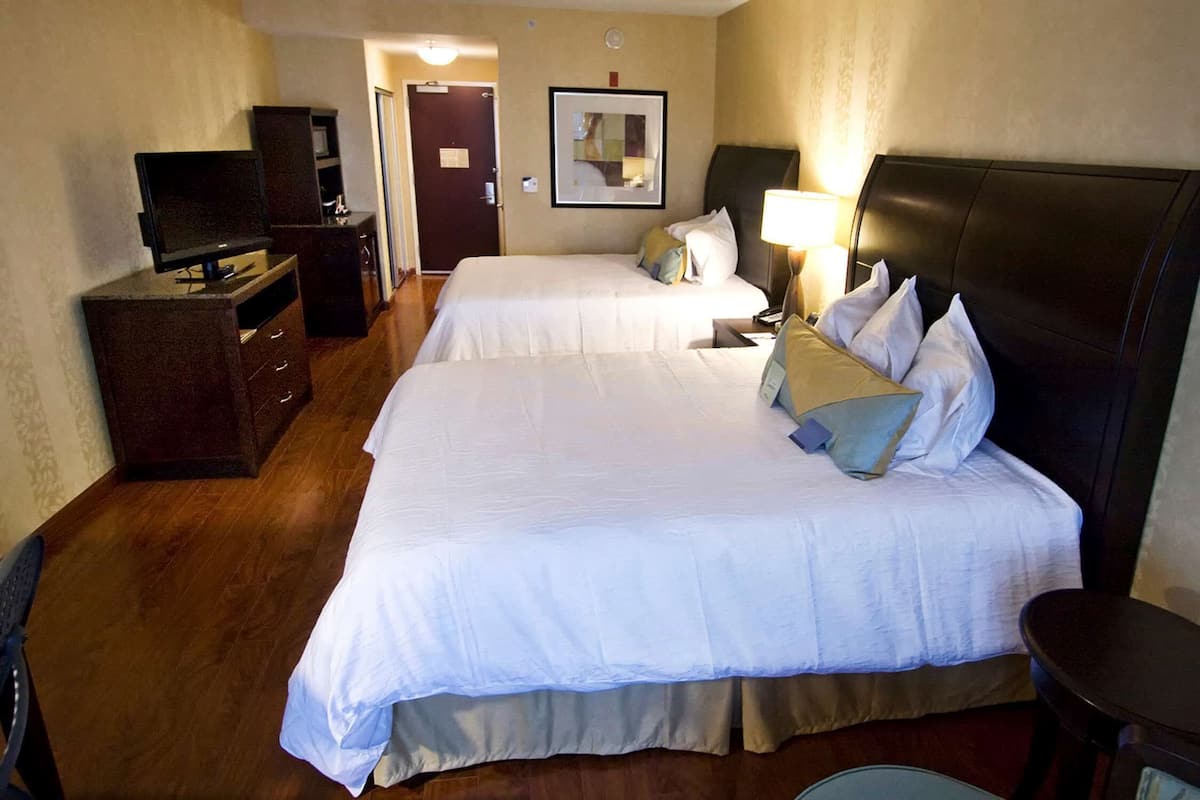 Ett hotellrum med två sängar, en TV, ett skrivbord och en spegel.