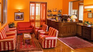 A cozy living room with striped sofas, a wooden coffee table, and a bar area with various bottles.