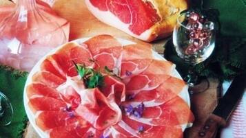 Una tabla de embutidos con diferentes carnes, pan y un vaso de agua.