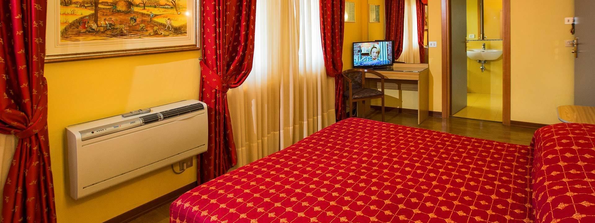 Habitación de hotel con cama, escritorio con computadora, baño y un cuadro en la pared.